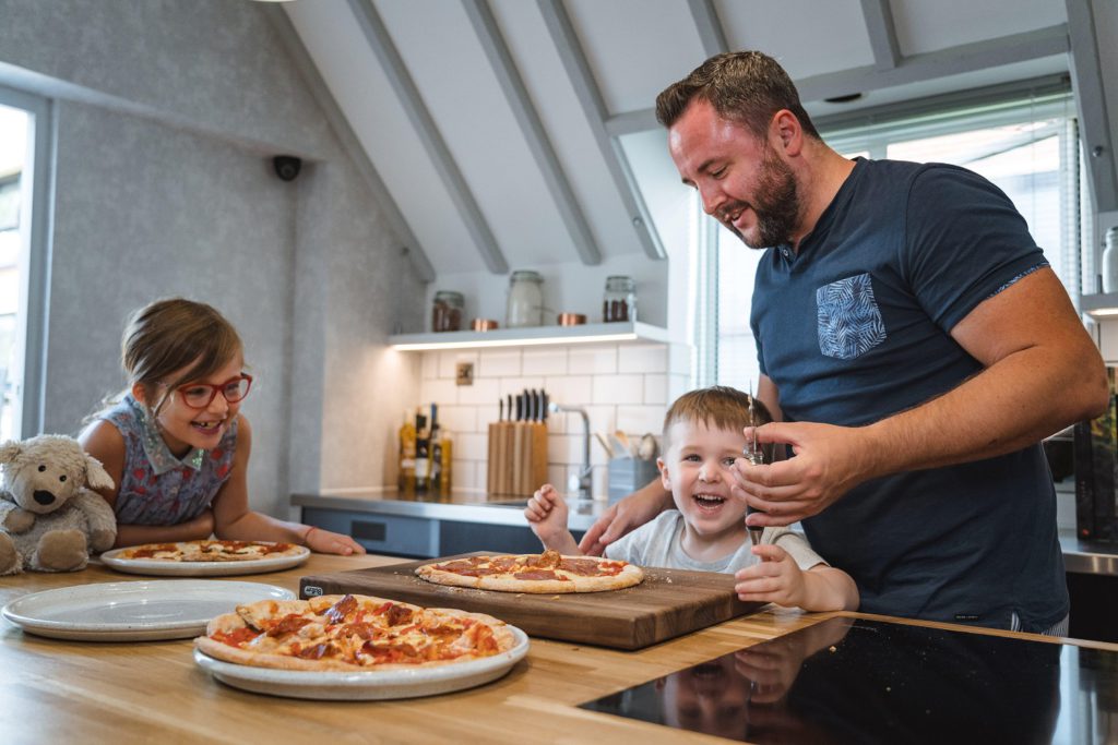 A family making pizza at home with a pizza kit