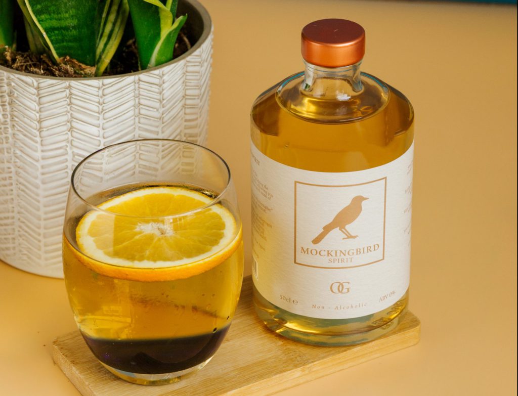 A small glass of Mockingbird Spirit next to a bottle.