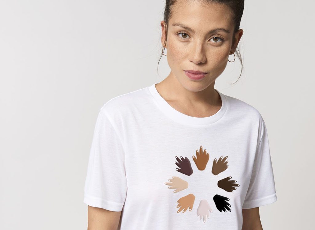A woman wearing the new 'Reaching out' t-shirt. The t-shirt features hands, of varying colours, in a circle.