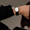 women with her hand behind her head showing off a women's black and silver fashion watch on her wrist