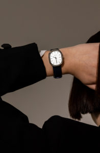 women with her hand behind her head showing off a women's black and silver fashion watch on her wrist